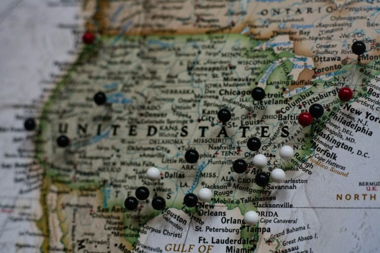 Paper map of the United States with black and red push pins marking several cities
