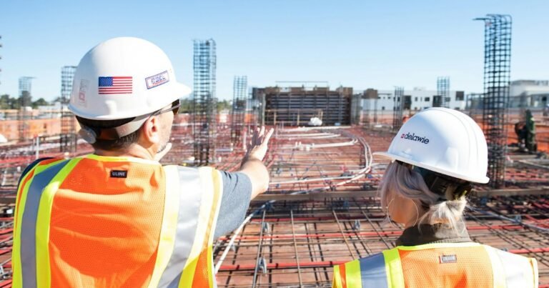 Two construction workers in hard hats and safety vests on a job site